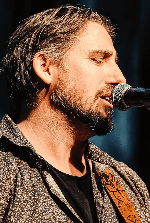 Ryan Inglis singing on stage with his acoustic guitar